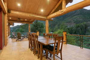 View of patio with outdoor dining space, a mountain view, ceiling fan, and a forest view