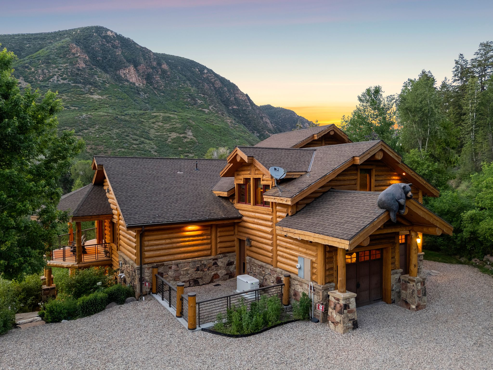 Split-log veneer, framed home with driveway, stone siding, a garage, a shingled roof, and a mountain view