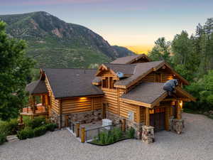 Log cabin with driveway, stone siding, a garage, a shingled roof, and a mountain view