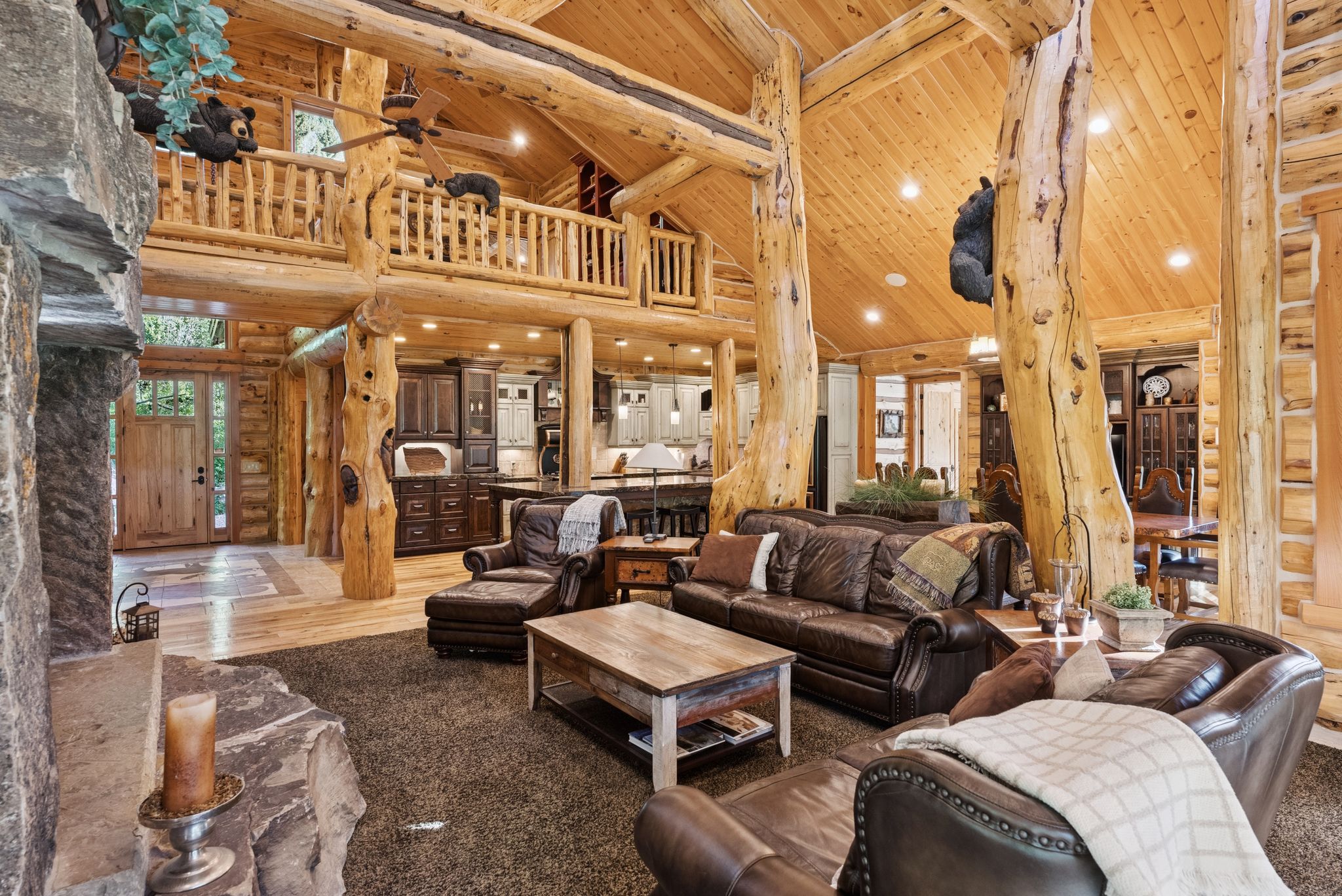 Living room with high vaulted ceiling, a tongue-in-groove ceiling with exposed beams, split-log walls, ceiling fan, and recessed lighting