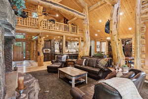 Living room with high vaulted ceiling, a wooden ceiling with exposed beams, log walls, ceiling fan, and recessed lighting