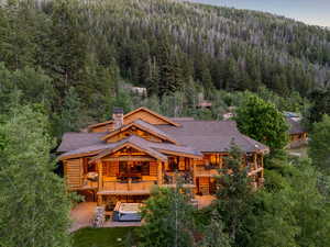 Back of property with a wooded view, log exterior, a chimney, and a shingled roof