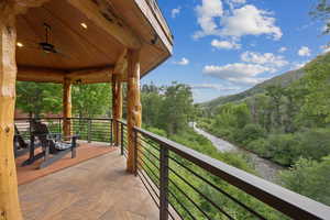 Balcony featuring a mountain view, ceiling fan, and a wooded view