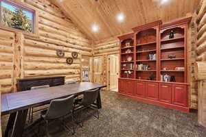 Home office featuring wood ceiling, high vaulted ceiling, dark colored carpet, rustic walls, and recessed lighting