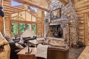 Living area with rustic walls, a wood stove, wood-type flooring, high vaulted ceiling, and ceiling fan