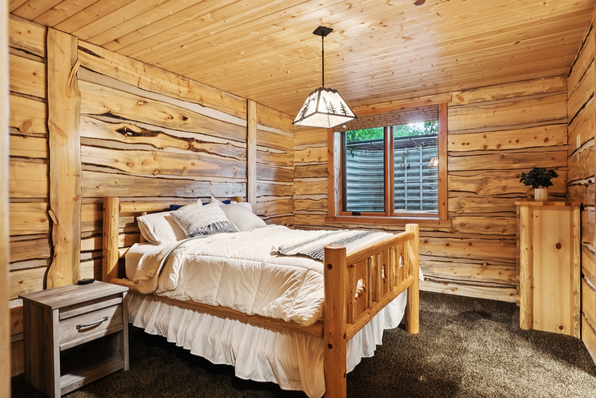 Carpeted bedroom with split log walls and tongue-in-groove ceiling