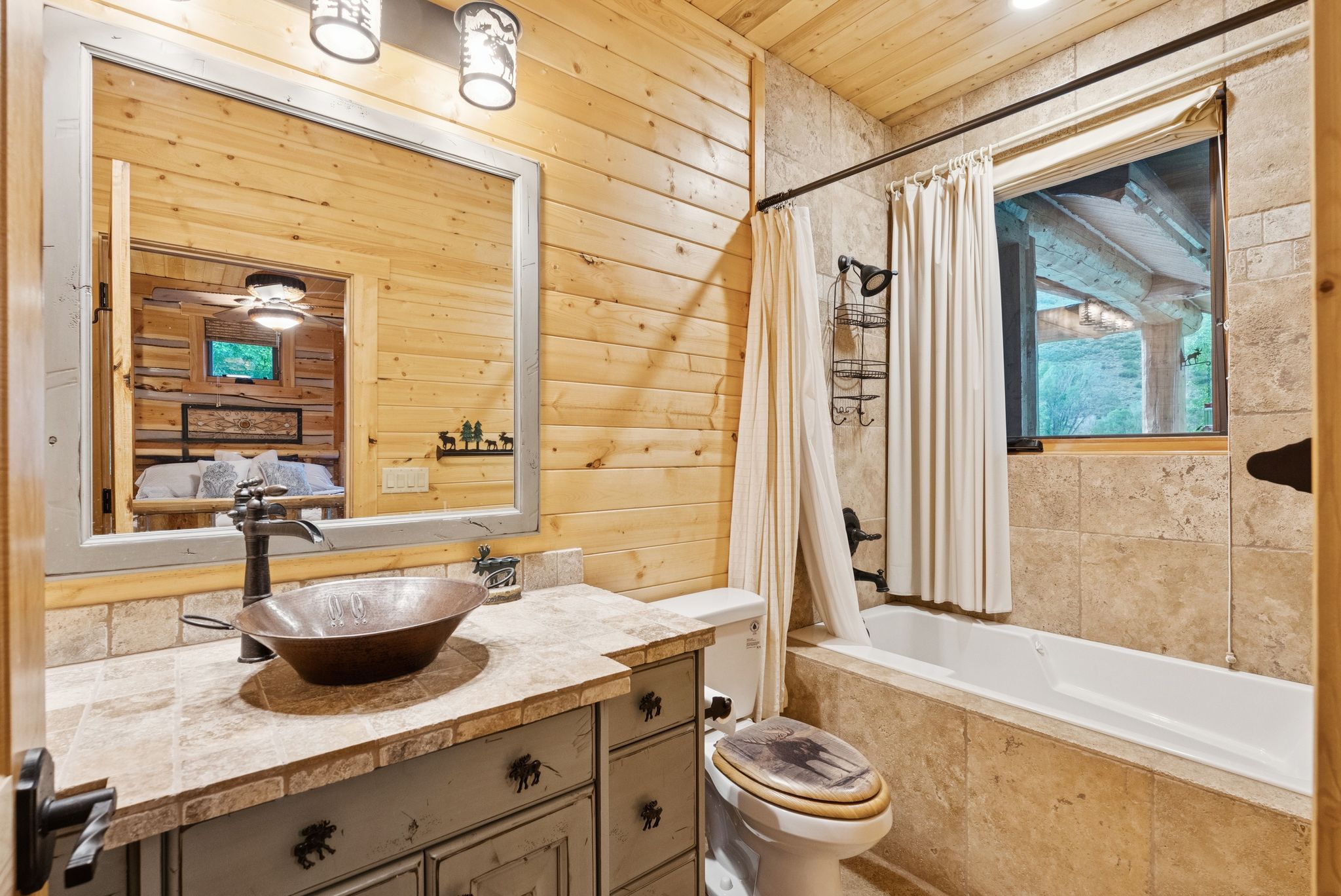 Full bathroom featuring wood walls, vanity, tiled shower / bath combo, and tongue-in-groove ceiling