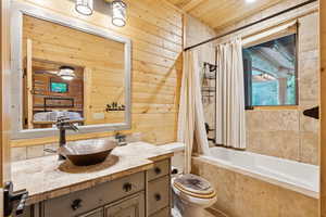 Full bathroom featuring wood walls, vanity, tiled shower / bath combo, and wood ceiling