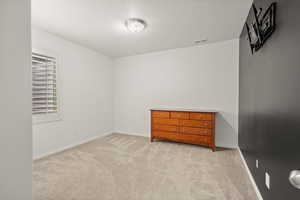 Unfurnished bedroom featuring light carpet and baseboards