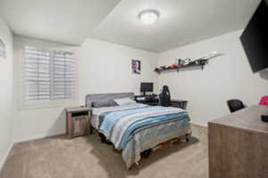 Bedroom featuring light colored carpet and an office area