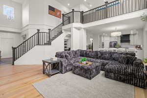 Living area with a chandelier, stairway, a high ceiling, recessed lighting, and light wood-type flooring