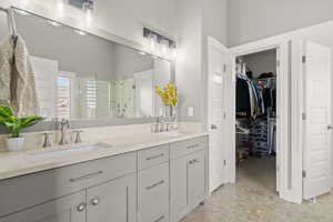 Bathroom with a shower stall, double vanity, and a walk in closet