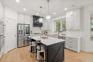 Kitchen with stainless steel appliances, backsplash, light wood-style flooring, light countertops, and recessed lighting
