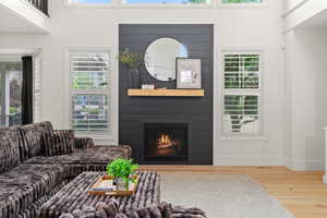 Living room with wood finished floors, healthy amount of natural light, a fireplace, and a high ceiling