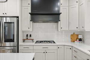 Kitchen featuring smart refrigerator, stainless steel gas stovetop, tasteful backsplash, and white cabinets