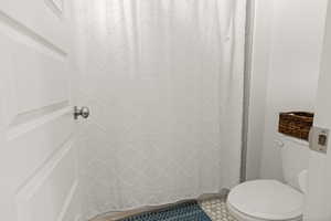 Bathroom featuring toilet and curtained shower