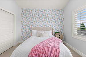Carpeted bedroom with wallpapered walls and vaulted ceiling