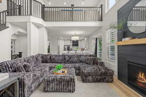 Living room featuring a high ceiling, a lit fireplace, wood finished floors, and recessed lighting