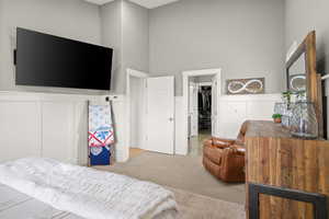 Bedroom featuring carpet, a walk in closet, a closet, wainscoting, and a decorative wall