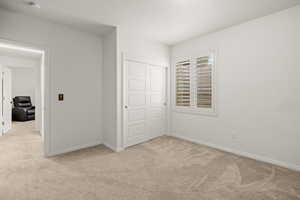 Unfurnished bedroom with light colored carpet and a closet