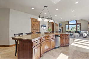 Kitchen with recessed lighting, a kitchen breakfast bar, a kitchen island with sink, light tile patterned floors, and pendant lighting