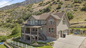 View of front facade featuring stone siding, a mountain view, concrete driveway, an attached garage, and stucco siding