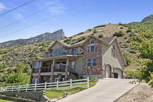 View of front of property with stone siding, stucco siding, a garage, concrete driveway, and a mountain view
