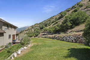 View of grassy yard featuring a deck with mountain view