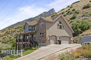 View of front of property featuring stone siding, a mountain view, a garage, concrete driveway, and stucco siding