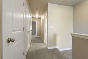Hallway featuring light carpet and baseboards