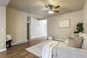 Living room featuring dark wood-style floors and a ceiling fan