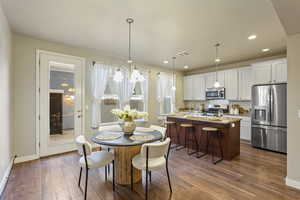 Dining room with dark wood-type flooring, a chandelier, and recessed lighting