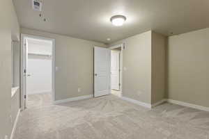 Unfurnished bedroom with light carpet, a spacious closet, and a closet