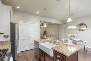 Kitchen with appliances with stainless steel finishes, dark wood-style floors, light stone counters, pendant lighting, and recessed lighting