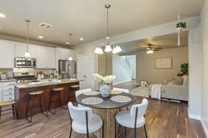 Dining area with dark wood-type flooring, stairway, recessed lighting, and ceiling fan