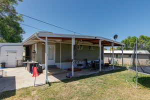 Rear view of property with a trampoline, a patio, a yard, brick siding, and a storage unit