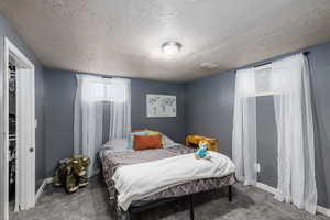 Carpeted bedroom with a textured ceiling and baseboards