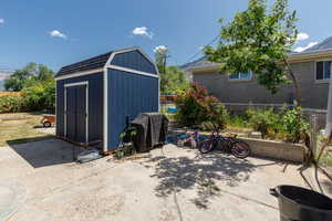 View of patio featuring area for grilling and a storage shed