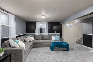 Living room featuring a textured ceiling,  new carpet, plenty of natural light, and stairs