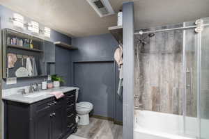 Bathroom with wood finished floors, vanity, bathtub / shower combination, and a textured ceiling