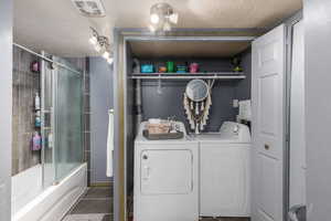 Washroom featuring independent washer and dryer, a textured ceiling, and tile patterned flooring with a full bath
