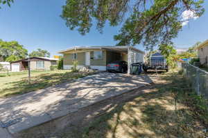 View of front of house featuring driveway, brick siding, and an attached carport