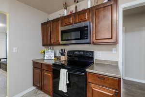 Kitchen featuring stainless steel microwave, black range with electric cooktop, and light wood finished floors