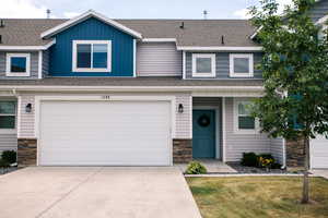 View of property with stone siding, concrete driveway, and a 2 car garage
