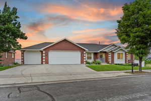 Single story home with brick siding, a garage, a yard, and concrete driveway
