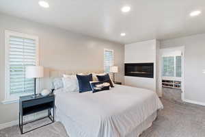 Bedroom featuring carpet, recessed lighting, and a large fireplace