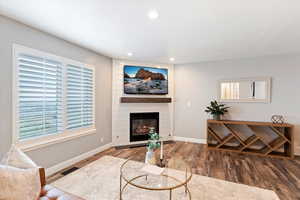 Living room with wood finished floors, healthy amount of natural light, recessed lighting, and a fireplace