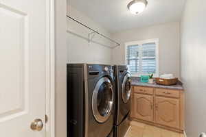 Washroom with washer and dryer and light tile patterned flooring