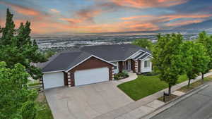 View of front of home with brick siding, an attached garage, concrete driveway, roof with shingles, and a mountain view