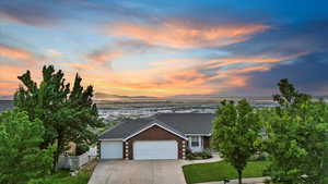 View of front facade featuring an attached garage, driveway, and brick siding